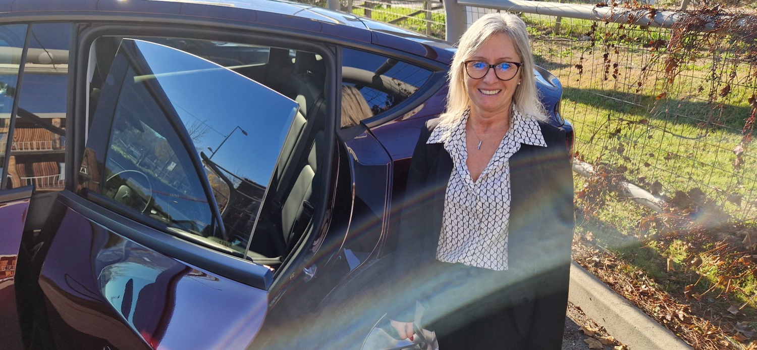 Frédérique, chauffeure privée VTC, devant sa Tesla à Cassis